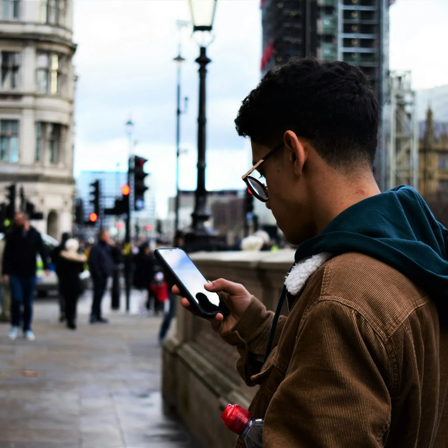 A man stops in a city street to look at something on his phone.