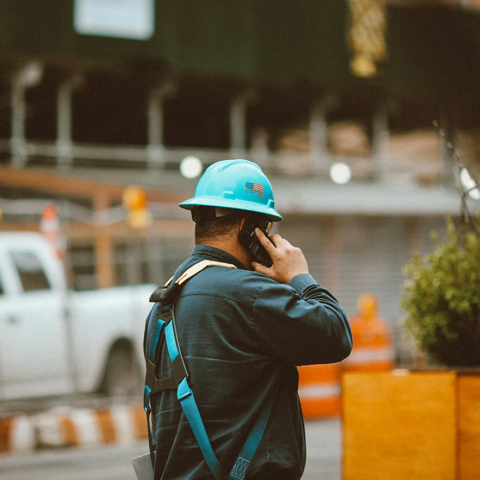 A worker in a hard hat takes a call beside his van.